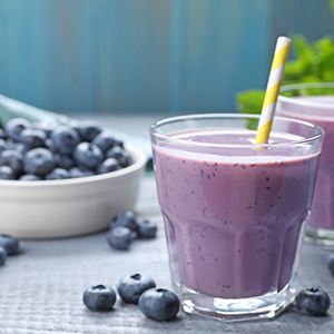Freshly made blueberry smoothie on grey wooden table
